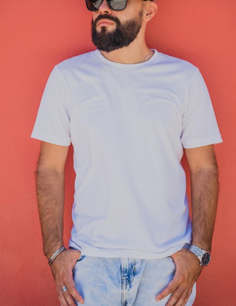 Male model with beard wearing white blank tshirt on the background of an orange wall