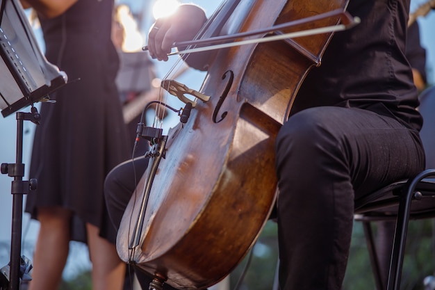 Musicista maschio che suona il violoncello in orchestra per strada