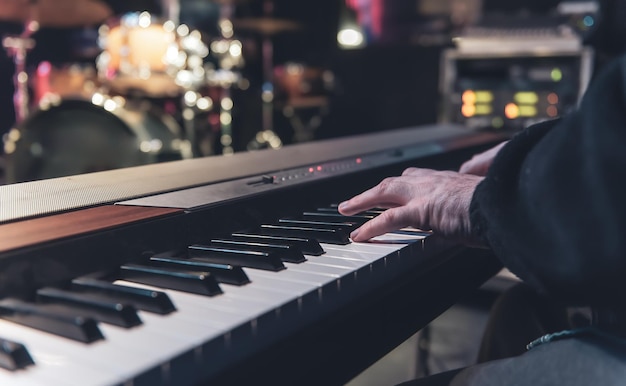 Male musician plays the electronic piano hands closeup