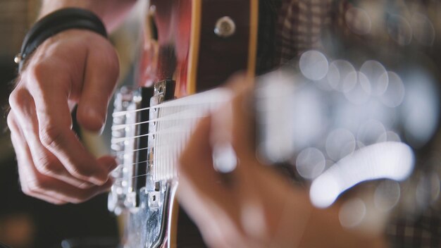 Male musician plays the guitar, hands close up, focus on the\
guitar fretboard, art concept