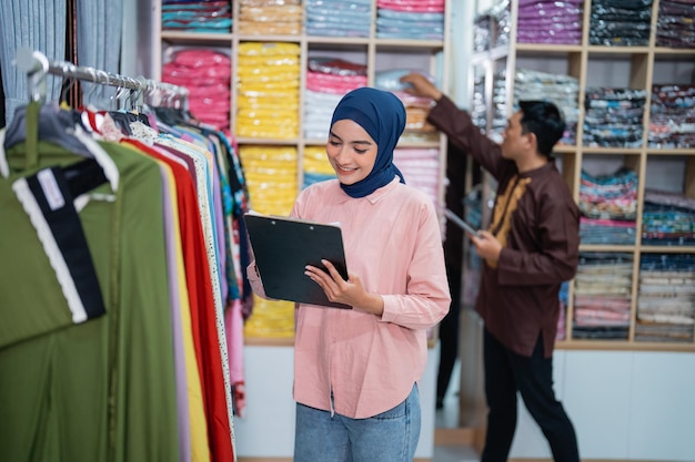 ファッションで製品の品質と在庫をチェックする男性とイスラム教徒の女性労働者