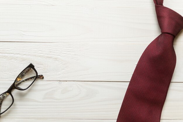 male necktie and eyeglasses lying on white wooden background