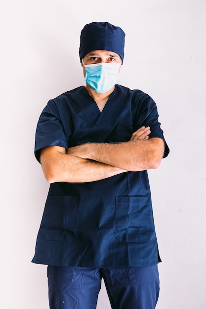 Male nurse, doctor or vet wearing blue mask and dark blue uniform in hospital, arms crossed, smiling. Medicine, hospital and healthcare concept.