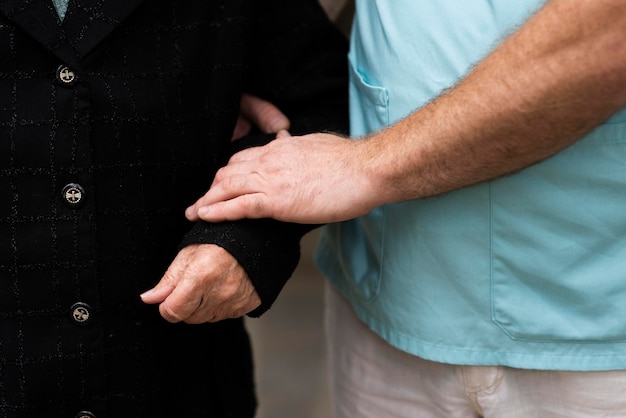 Male nurse holding older woman's arm