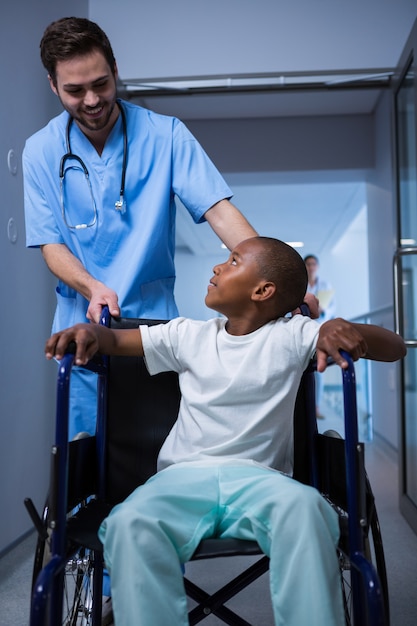 Male nurse interacting with child patient in corridor