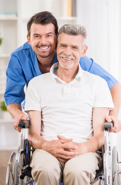 Male nurse talking with senior patient in wheelchair.