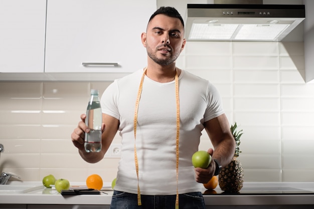 Male nutritionist keeps a bottle of water and an apple in the kitchen