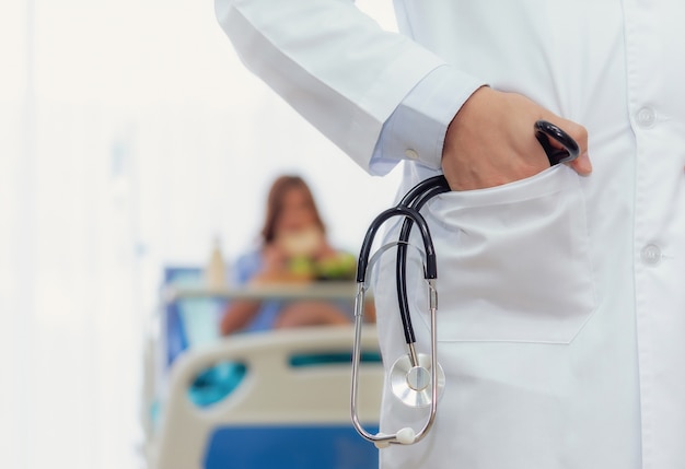 Professionisti di medico maschio ostetrico è in possesso di sfondo sfocato stetoscopio e donna incinta.
