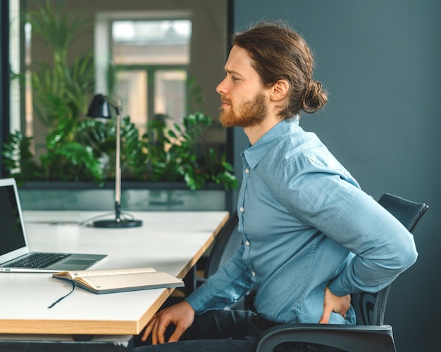 Male office worker suffering from terrible pain in lower back