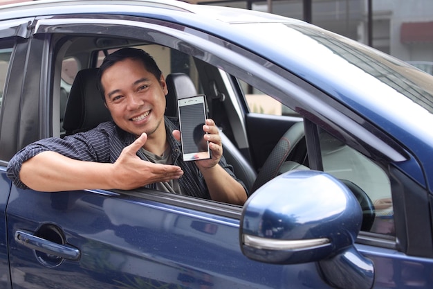 Male online taxi driver showing phone screen while sitting in a car