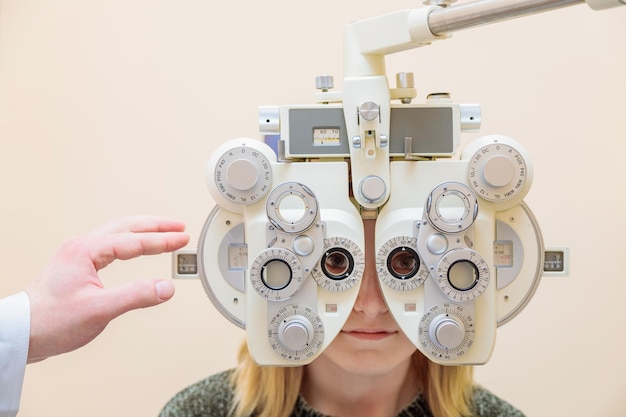 A male ophthalmologist checks a girls eyesight using a phoropter Vision treatment