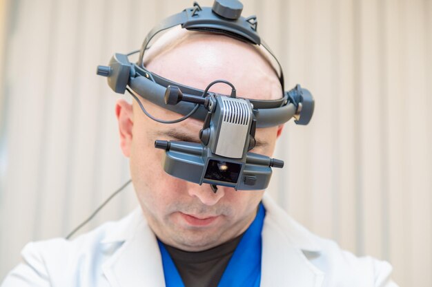 Photo a male ophthalmologist checks a patients vision with a binocular ophthalmoscope