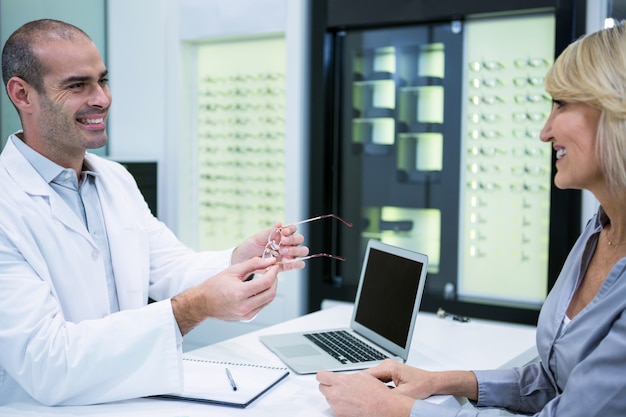 Foto optometrista maschio che parla con paziente femminile