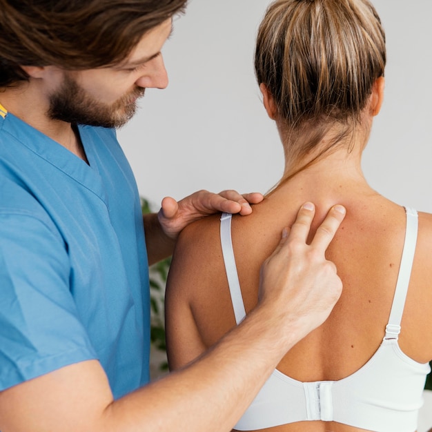 Foto terapista osteopatico maschio che controlla la colonna vertebrale del paziente femminile