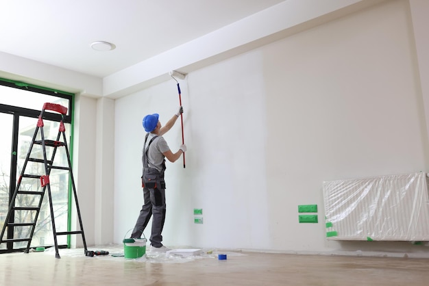 Male painter paints house wall with roller brush decoration and improvement interior concept