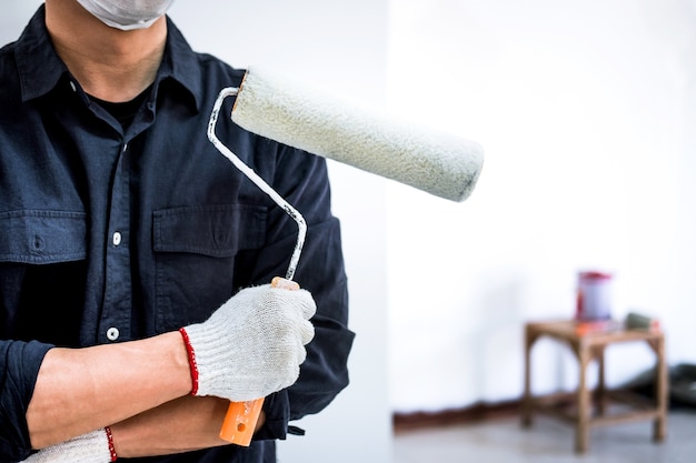 Male Painter with arm crossed holding paint roller