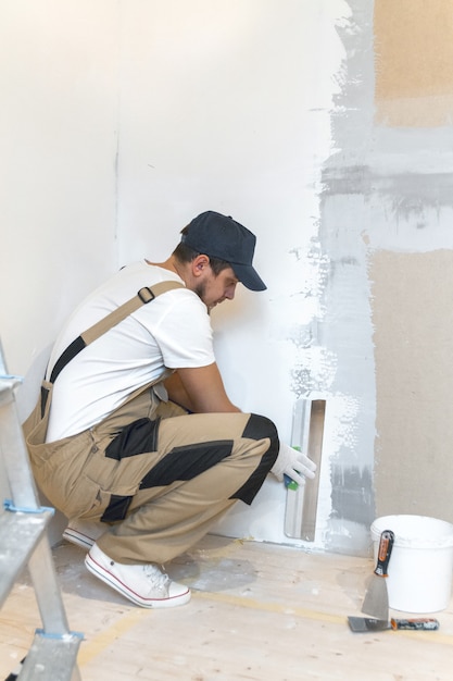 Male painter with a spatula in his hands makes repairs in home. Room renovation concept.