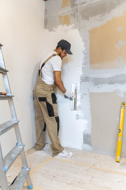 Male painter with a spatula in his hands makes repairs in home. Room renovation concept.