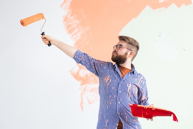 Male painting the wall with paint roller. Portrait of a funny guy painting wall in her new apartment