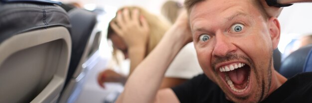 Male passenger holding his head and shouting on plane