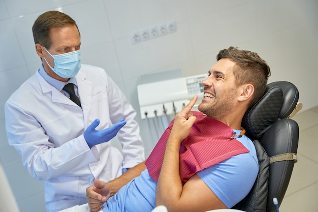 Male patient and his trusted dentist having conversation during checkup