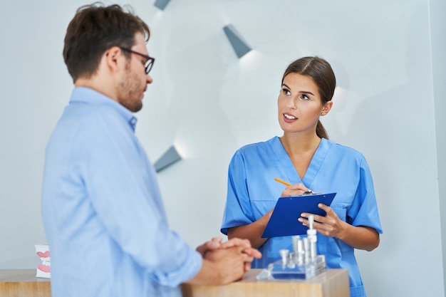 male patient signing documents in dental clinic