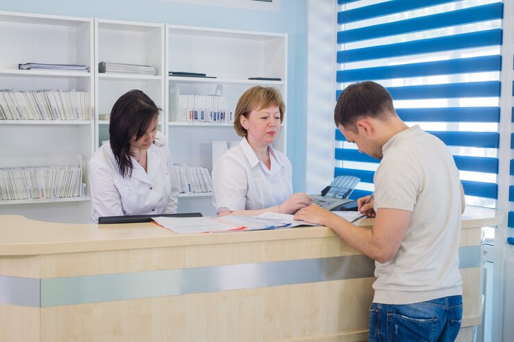 Male patient with doctor and nurse at reception desk in hospital