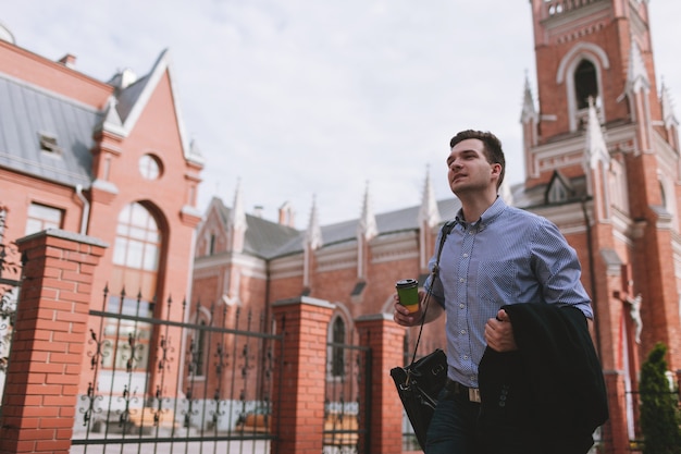 Male pedestrian walking on street. Young man with coffee outside. Nature concept