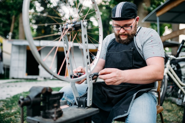 Male person adjusts bike spokes and wheel