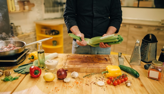 Male person cooking meat with vegetables in a pan