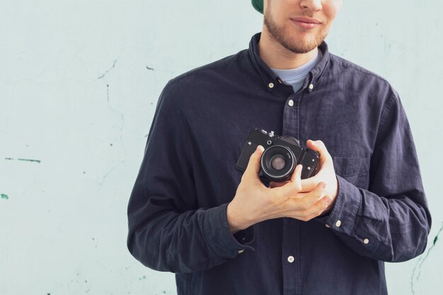 A male person holding a vintage camera and djust settings, old fashioned trend