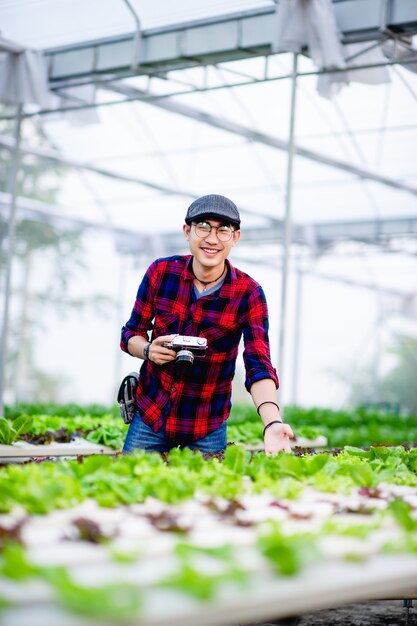 A male photographer is taking pictures in his salad garden and enjoying photography.