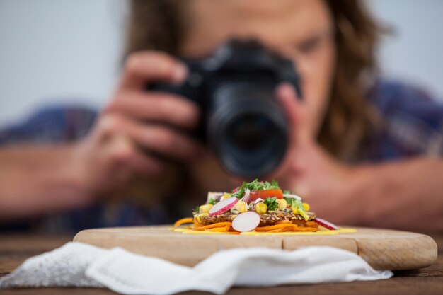 Мужской фотограф фотографируя еду