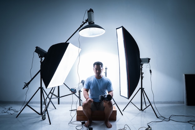 Photo male photographer in photography studio surrounded by lighting equipment