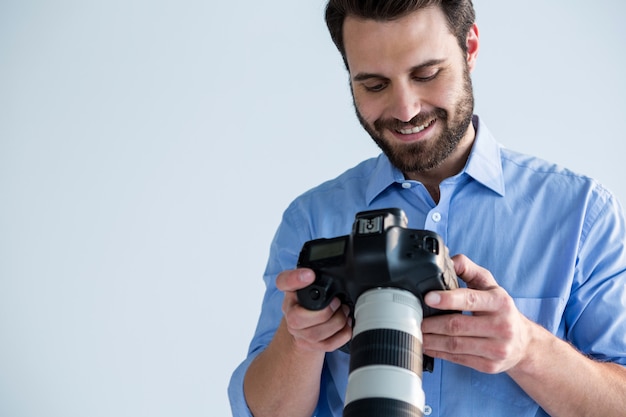 男性カメラマンがデジタルカメラで撮影した写真を確認する
