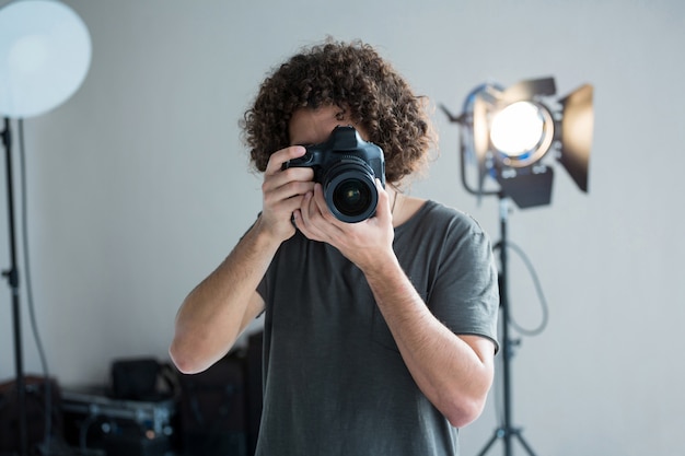 Fotografo maschio con la macchina fotografica digitale in studio