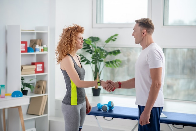 Male physiotherapist and female patient shaking hands