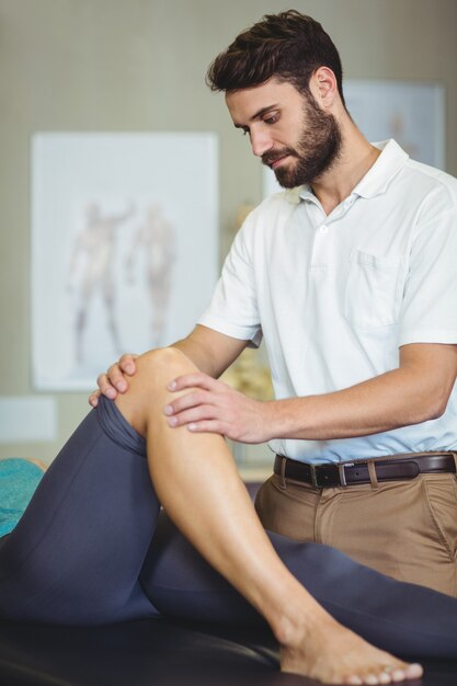 男性の理学療法士が女性患者に膝マッサージを与える