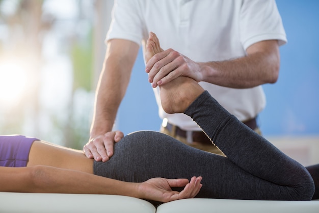 Male physiotherapist giving knee massage to female patient