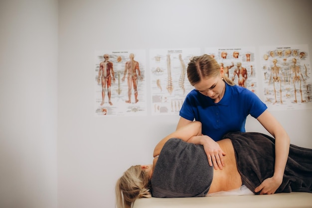 Foto fisioterapista masticando la schiena di una donna anziana nell'ufficio medico foto di alta qualità