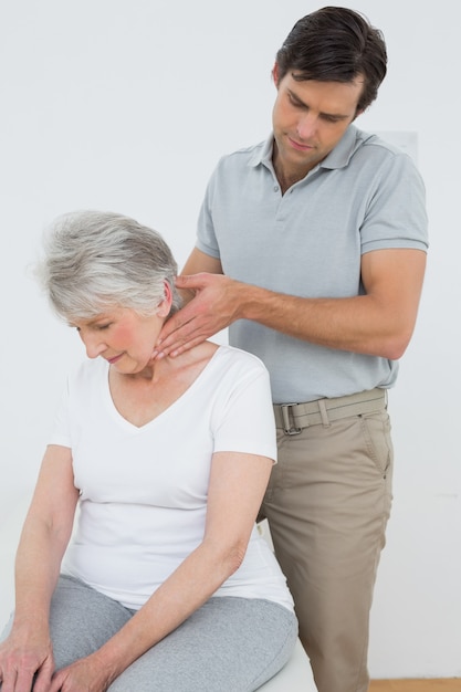 Male physiotherapist massaging a senior womans neck