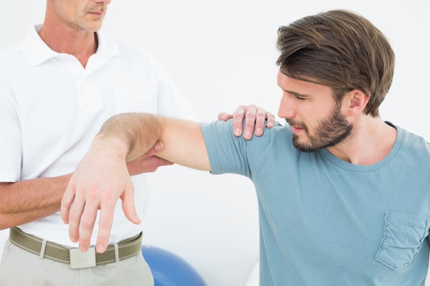 Male physiotherapist massaging a young mans arm