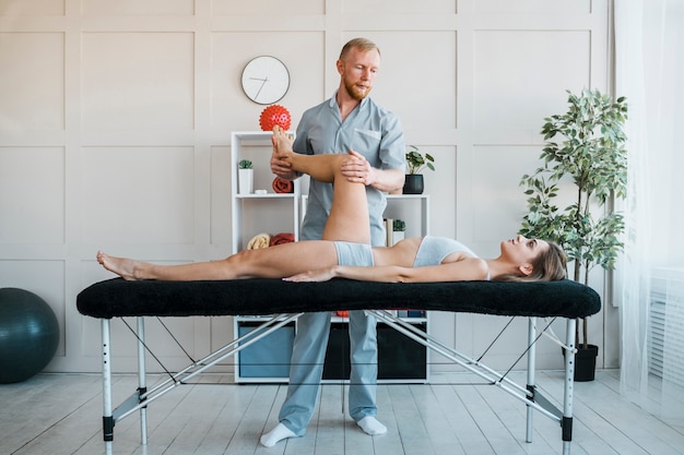 Male physiotherapist performing exercises on woman at the clinic