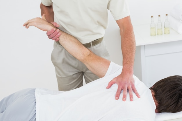 Male physiotherapist stretching a mans hand