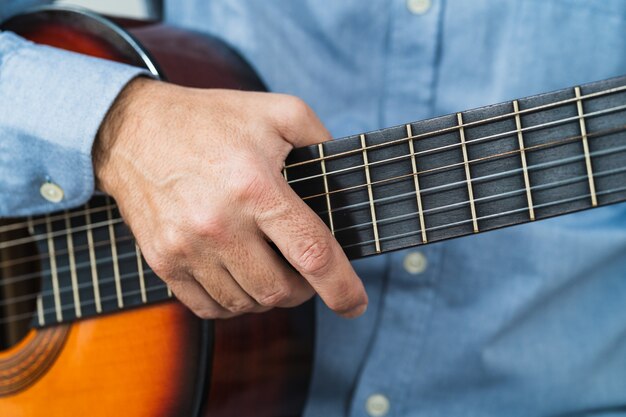 Maschio che prende in mano la chitarra. imparare con un corso online