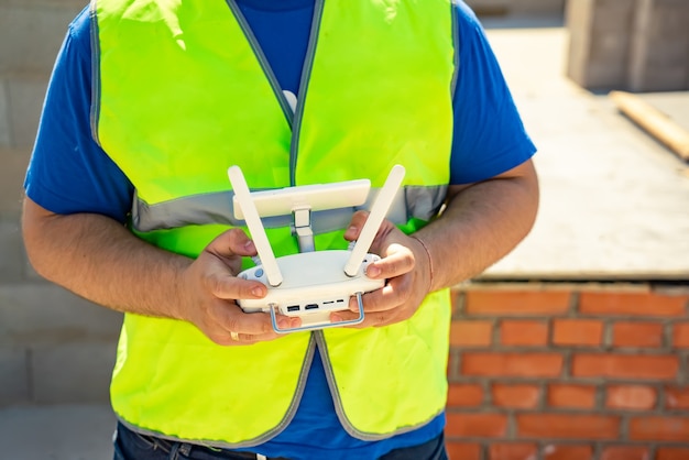 Quadcopter drone volante pilota maschio in piedi con telecomando all'aperto
