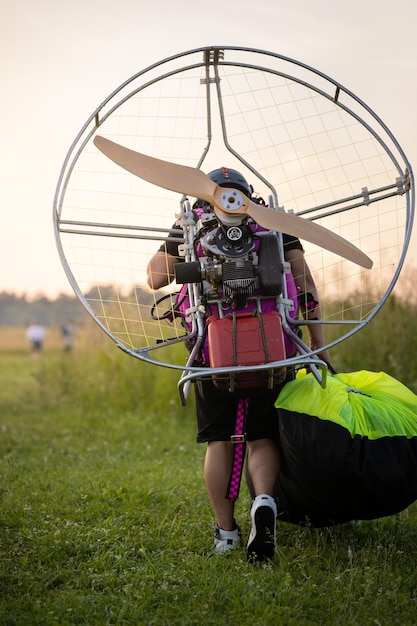 Photo a male pilot is preparing a gasolinepowered paralet for paragliding flights