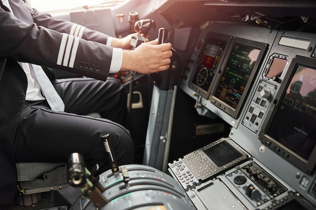 Male pilot use steering wheel to fly on passenger airplane jet. Interior of cockpit in modern plane with dashboard and air navigation. Man wear uniform. Civil commercial aviation. Air travel concept