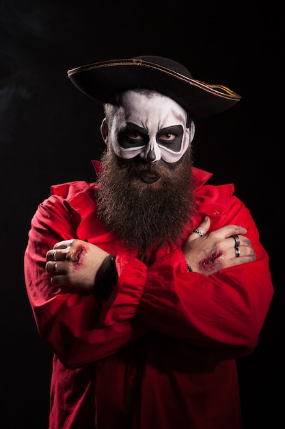 Male pirate with a spooky disguise over black background for halloween.