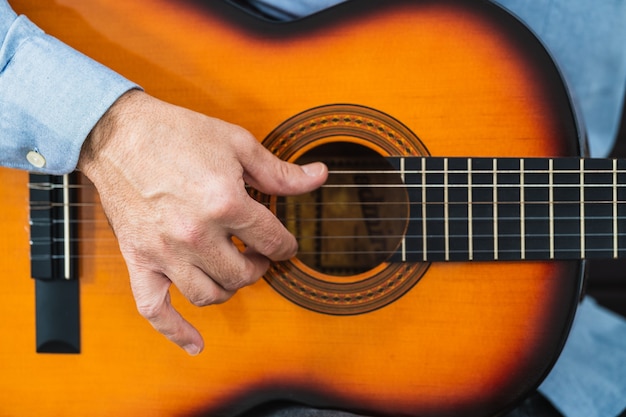 Male playing the guitar strings. Practicing and learning with an online course